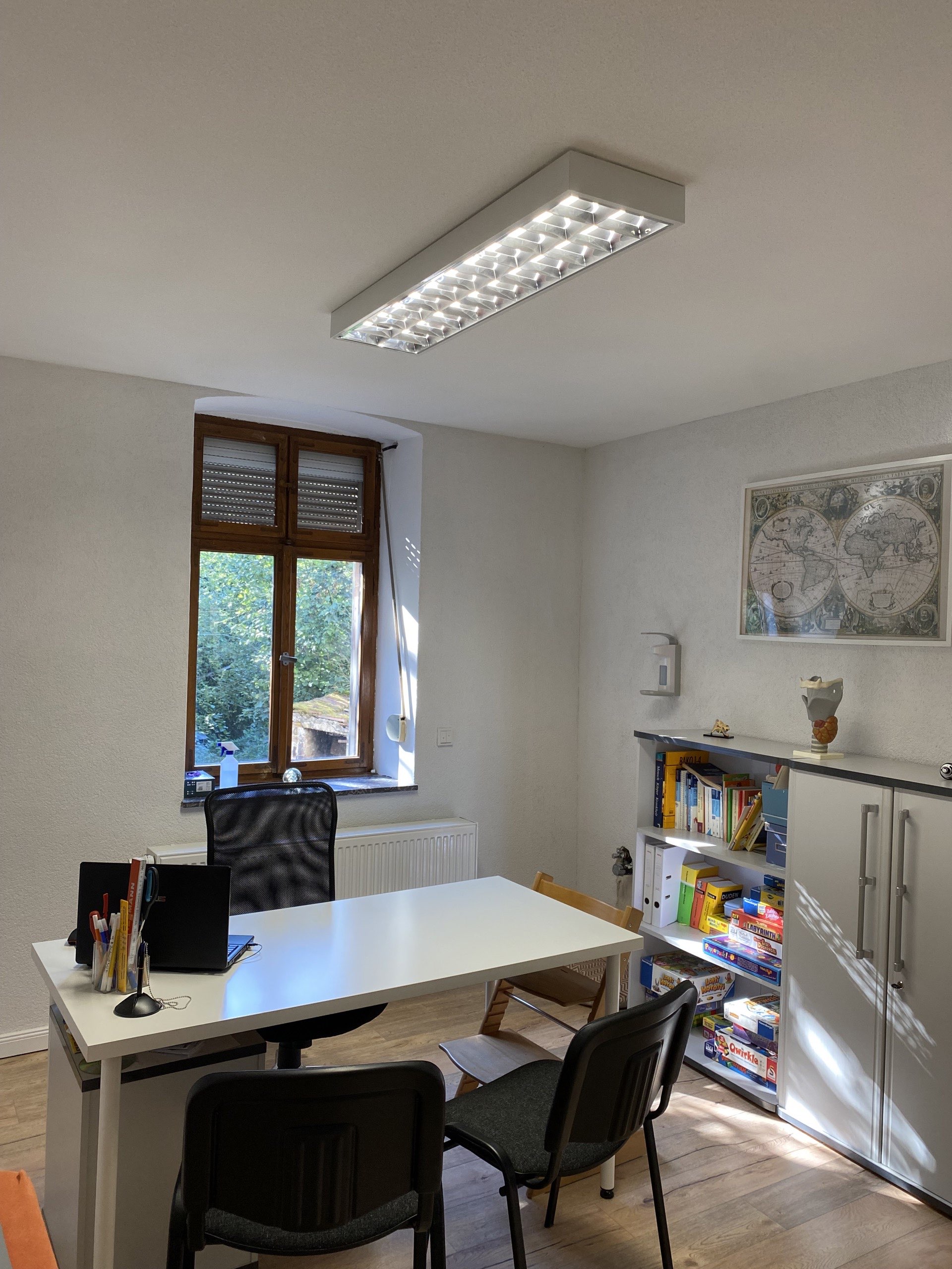 Behandlungsraum mit Therapieliege und Schreibtisch